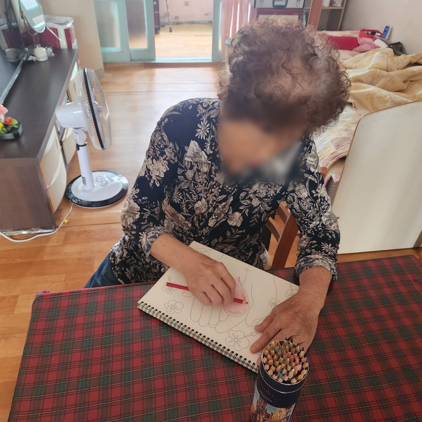 거실에서 노트에 그림을 그리는 어르신